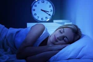 Vrouw slaapt in bed met klok op de achtergrond