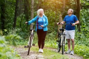Oudere man en vrouw met fiets in bos